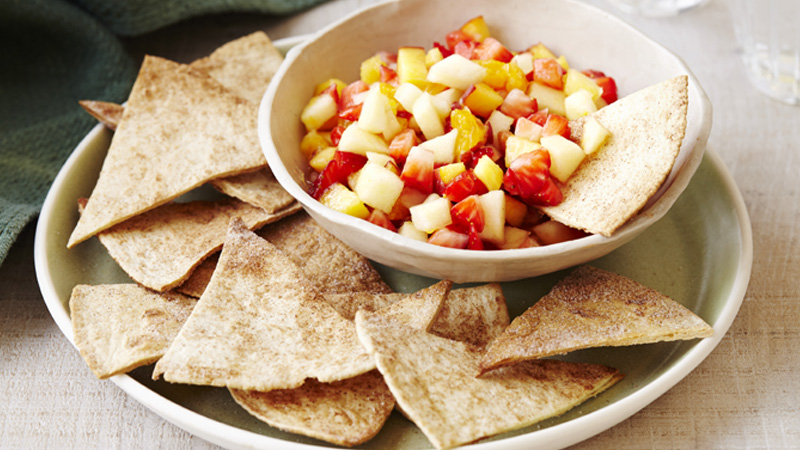 a bowl of fruit salad served with cinnamon crisps in a white plate