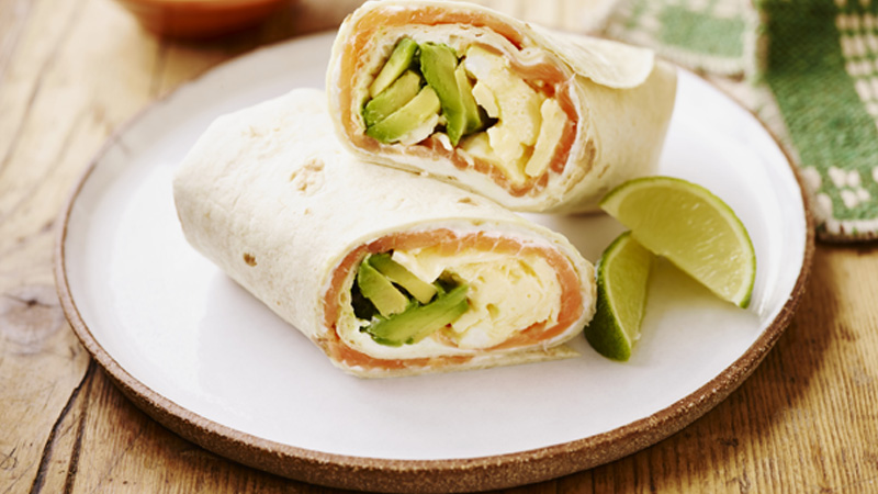 Smoked Salmon, Egg and Avocado Breakfast Burritos served on a white plate with lime slices